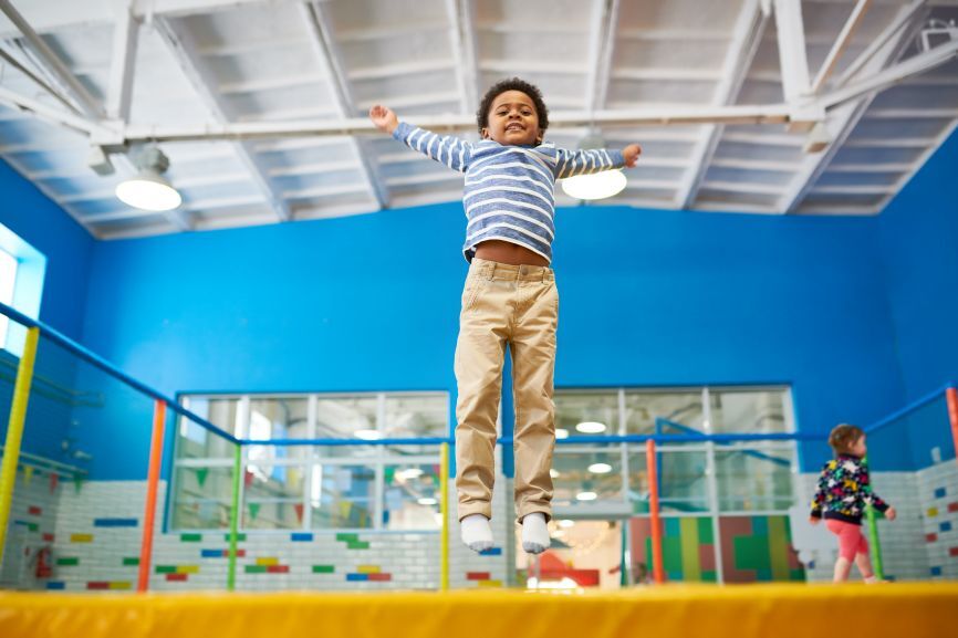 Child jumping joyfully on an indoor bouncy castle in a bright play area, provided by Bizi Bouncers UK for Best Indoor Venues for Bouncy Castle Parties in London & Essex.