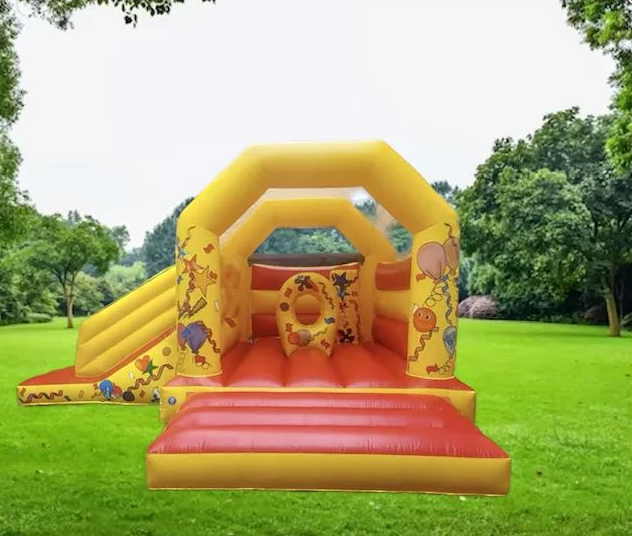 Bright yellow and red bouncy castle with slide, decorated with balloons and party designs, set up on green grass in Loughton by Bizi Bouncers UK.