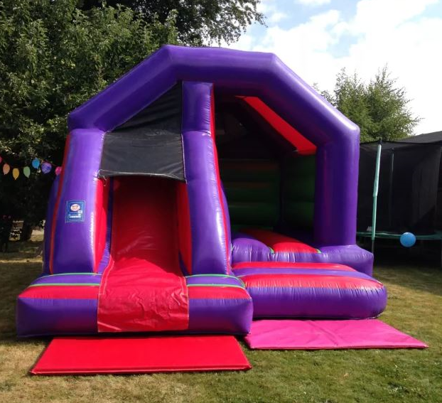 Purple and red inflatable with slide setup on grass by Bizi Bouncers UK for Bouncy Castle hire Woodford events and parties.