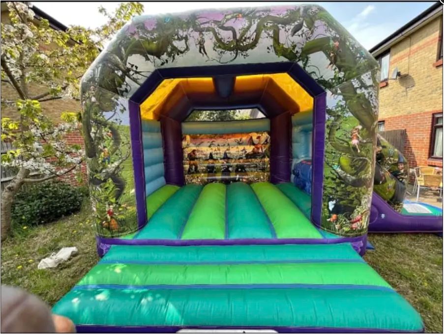Enchanted bounce and slide bouncy castle in pink and purple with side slide, perfect for fairy-tale themed parties