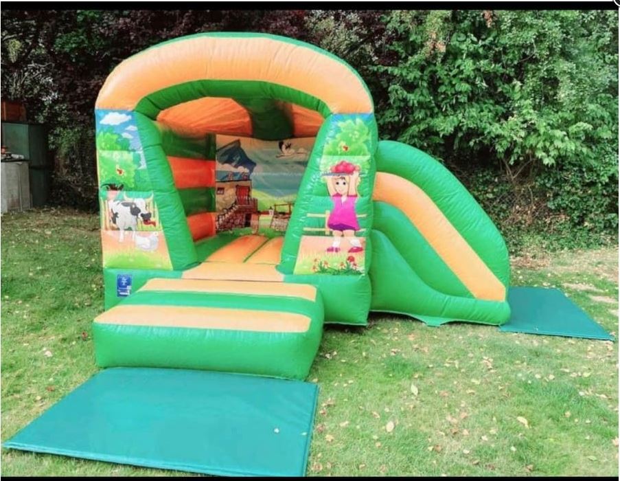 Farm-themed bounce and slide bouncy castle with front-facing slide and colourful barnyard design