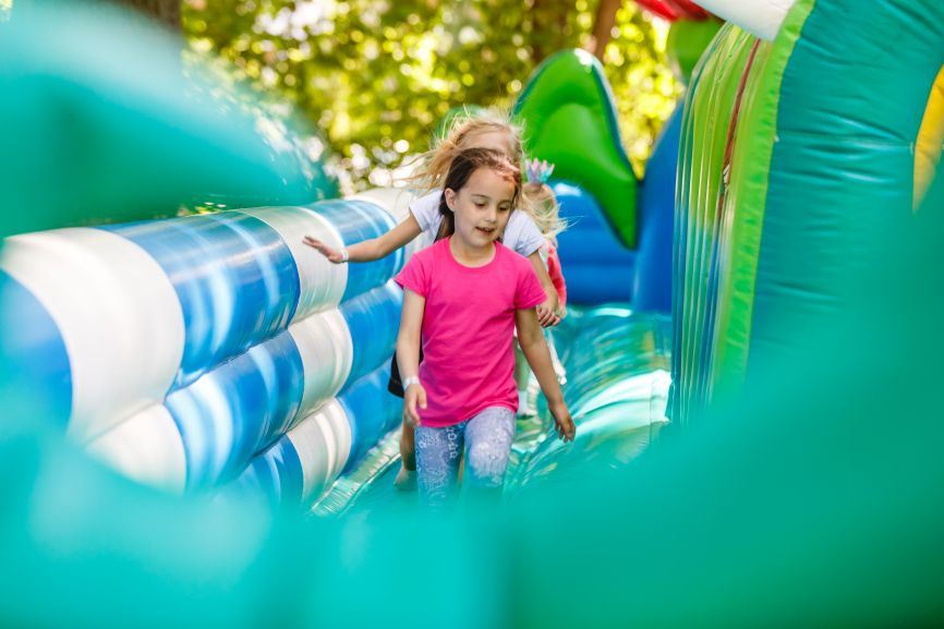 Garden Parties vs Hall Parties – Which Is Better for Kids? With Bouncy Castles, showing children enjoying a colourful inflatable at a kids’ party by Bizi Bouncer UK.