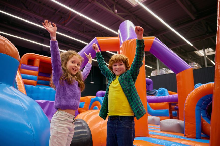 Children playing on a colourful indoor bouncy castle setup by Bizi Bouncers UK, illustrating how much space you need for an indoor bouncy castle according to the complete guide.