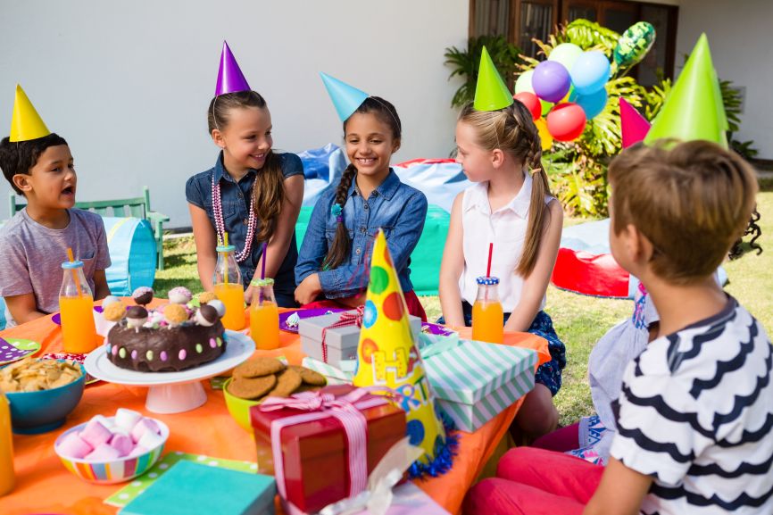 Summer party food table with fruit skewers, cupcakes, popcorn, and lemonade for kids